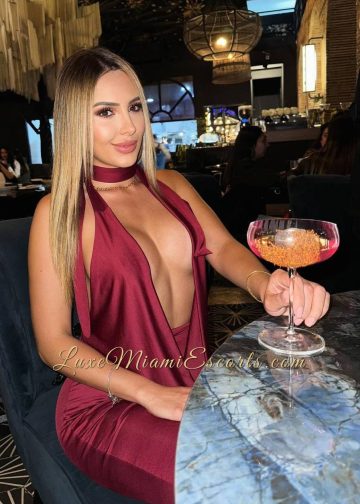 Amateur photo of Louisa posing at the restaurant table in sexy burgundy dress