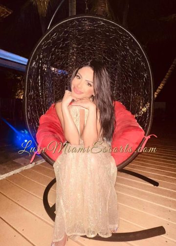 Miranda sitting on a lounge chair in beige dress with a beautiful smile