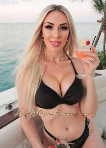 Blonde Ukrainian model Ruslana posing in black swimwear with a tropical drink in her hand