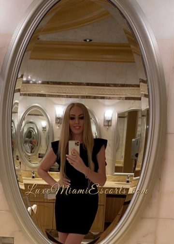 Selfie taken in the mirror of beautiful blonde escort model Ruslana, dressed in sexy short black dress