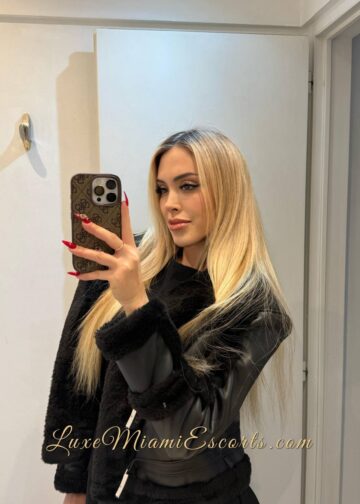 Selfie of Teresa taken in a bathroom mirror, wearing black jacket