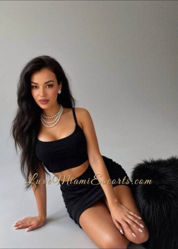 Elena sitting on the floor, wearing short black skirt and black top