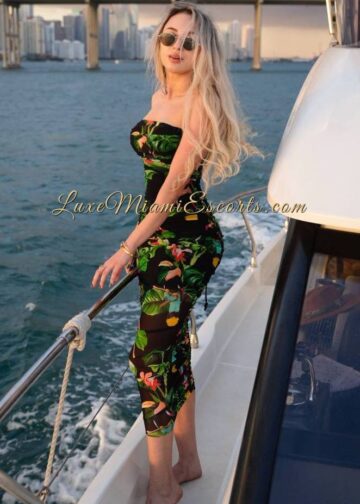 Amateur photo of blonde Miami escort Irina posing on a yacht in black and green dress