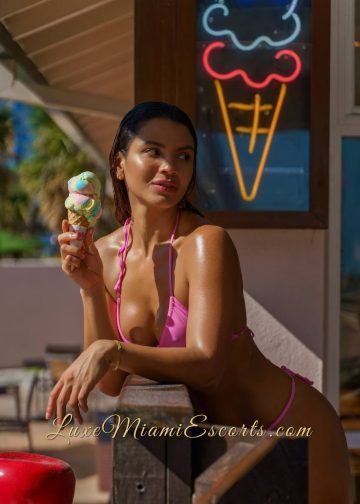 Andrea eating ice cream by the beach in her pink swimwear