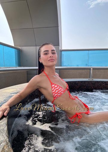 Beautiful and slim brunette escort girl Elza sitting in hot tub in red and white swimwear
