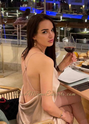 Amazing Miami Russian escort girl Inna having glass of red wine, wearing sexy beige dress