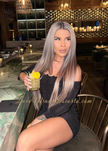 Amateur photo of Miami escort Stefani sitting at the bar, wearing short black dress