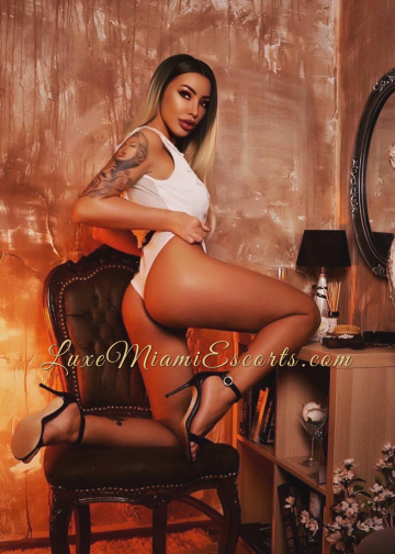 Professional photo of beautiful Miami Romanian escort Adita, posing on a chair in white lingerie and black high heels