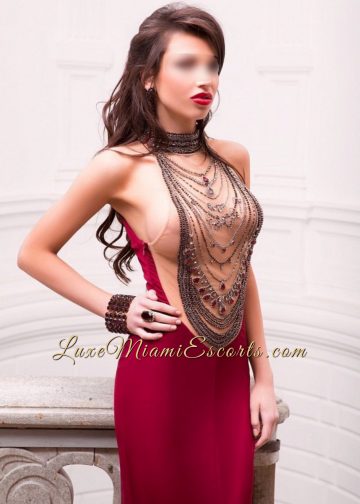 Camila - busty brunette Miami escort model with long brown hair posing in her evening dress