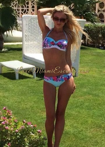 Slim and sexy Miami blonde escort Isabella standing in her colorful swim wear